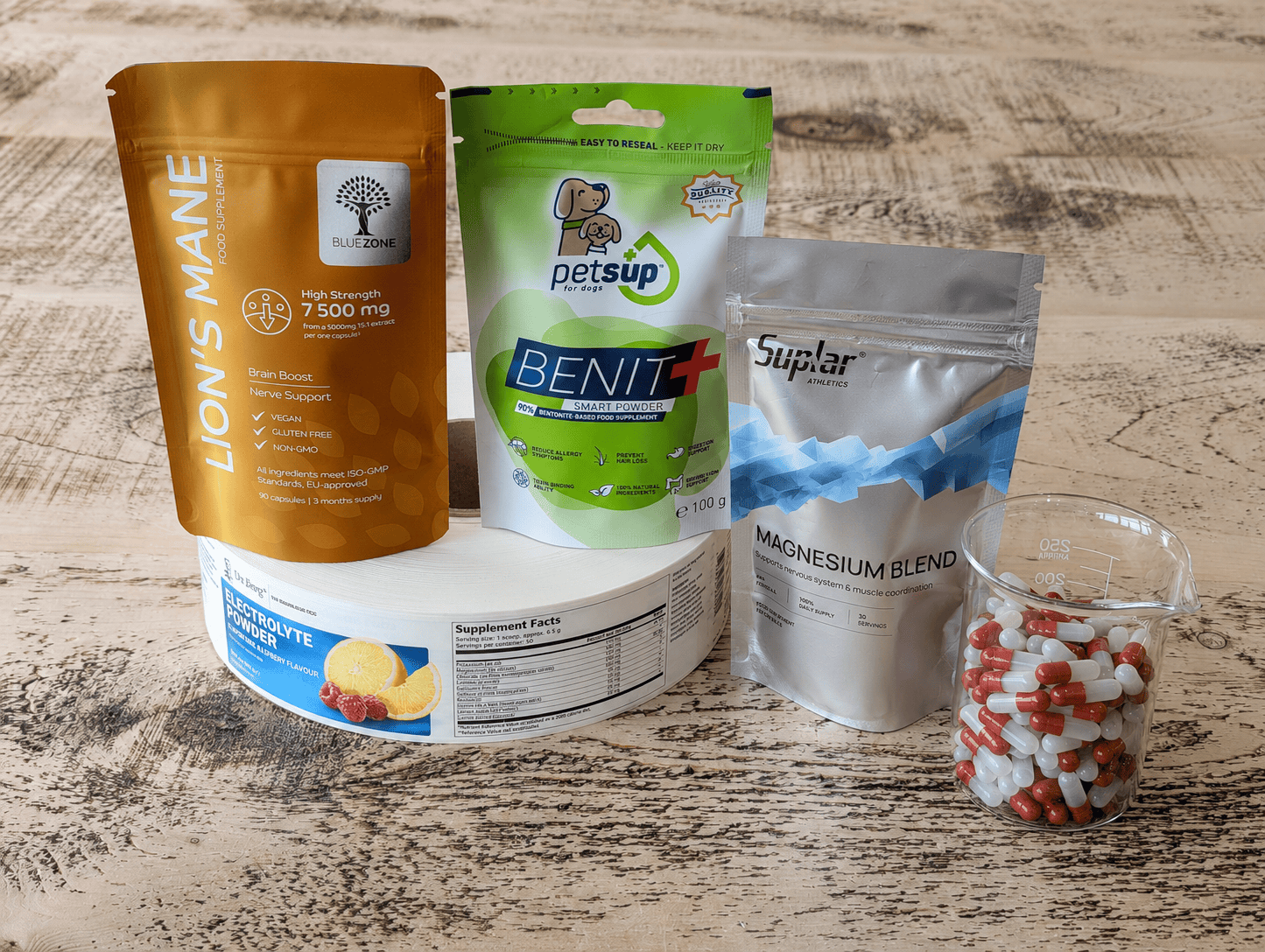 Various health supplement packages, capsules, and powders arranged on a wooden surface.